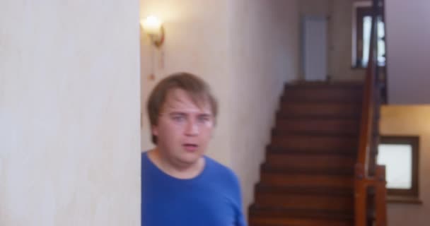 Νεαρός σε κατάσταση πανικού τρέχει μέσα στο δωμάτιο και γυρίζει το κεφάλι του από άκρη σε άκρη, κοιτάζοντας γύρω και προσπαθώντας να καταλάβει τι συνέβη. Υπερβολική αντίδραση του τύπου με το μπλε μπλουζάκι — Αρχείο Βίντεο