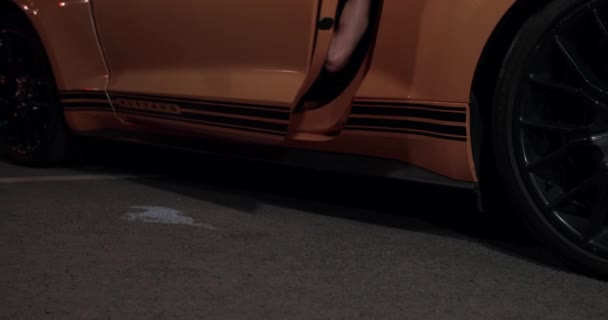 06 de setembro de 2021, São Petersburgo, Rússia: A porta do carro abre e bêbado jovem cai no chão de amarelo Ford Mustang, de perto. Conceito de entretenimento e estilo de vida pouco saudável — Vídeo de Stock