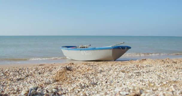 Oude lege boot staan op het strand gewassen door golvende zee golven — Stockvideo