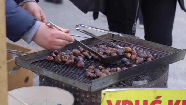 La gente locale arrosto castagne per i turisti sulla griglia sulla strada — Video Stock