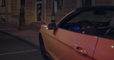 Bir kaza geçirmiş ve kafası direksiyonda bilinçsiz bir şekilde oturuyor. Araba elektrik direğine çarptı ve duman tütüyor. İhmalden ya da alkol zehirlenmesinden dolayı araba kazası.