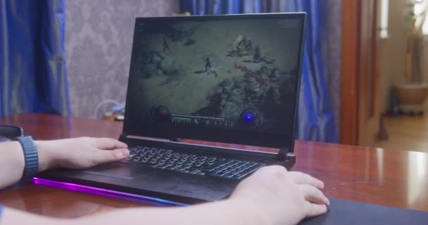 Rostov, RUSKO - 13. listopadu 2021: Gamer rychle stiskne tlačítka myši a klávesnice při hraní Diablo 2 Vzkříšení na notebooku s přáteli přes internet, pohled zezadu — Stock video