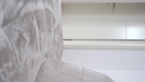 Chiot de teckel drôle en peignoir confortable et la tête enveloppée avec une serviette douce s'écoule sur le canapé gris clair dans la chambre. plan vertical — Video
