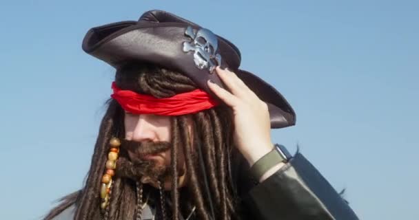 Пиратский капитан в взмотанной шляпе ладонями к голубому небу — стоковое видео