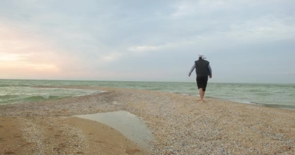 Пират гуляет на пляже с мягким песком у моря на закате — стоковое видео