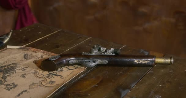 Пірат бере револьвер, лежачи на дерев'яному столі біля старої карти — стокове відео
