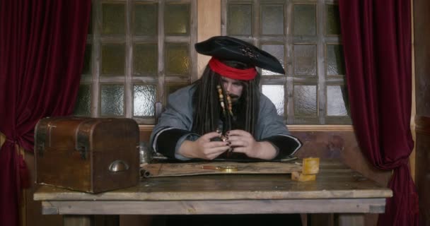 Pirate captain takes gold from treasure chest looking at map — Stock Video