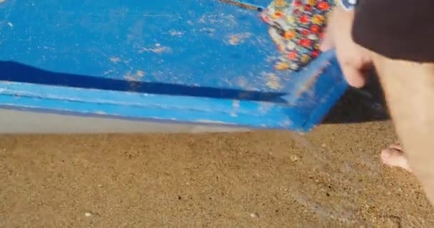 Pieds nus pirate pousse bateau en mer laissant une empreinte sur le sable — Video