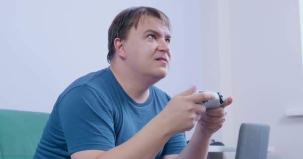 Plump man spelar TV-spel med controller och blir arg — Stockvideo
