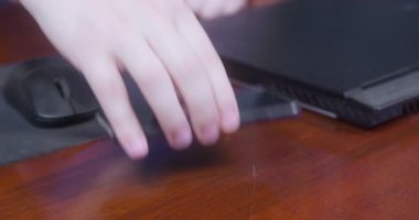 Kişi dikkatle bilgisayar faresinin yanındaki masaya akıllı telefonu koyar ve ofiste çalışmaya başlamak ya da evde oyun oynamak için bilgisayar panelini açar, kapatın.
