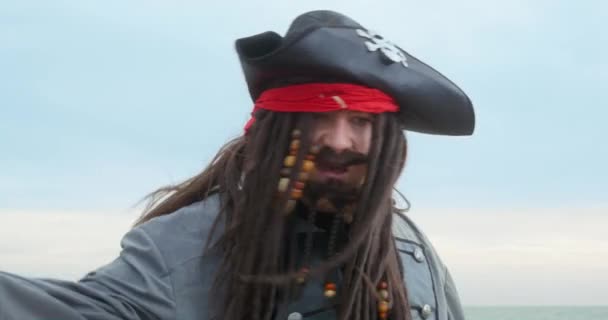 Lajdácký pirát s nataženými kloboučkovými vlnami rukou na mořské pláži — Stock video