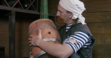 Uzun kızıl bıyıklı ve beyaz bandanalı mutlu bir korsan. Gemi kabininde romlu ahşap fıçıyı öpüyor.