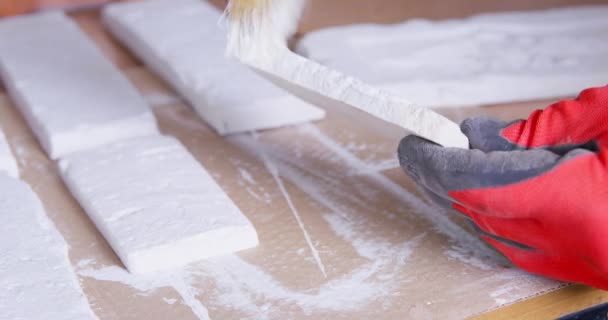 작업자는 나무 식탁에 놓여 있는 흰 회반죽 벽돌을칠 한다 — 비디오