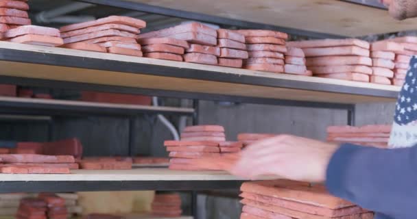 Worker puts decorative brick casts on wooden shelves — Stock Video