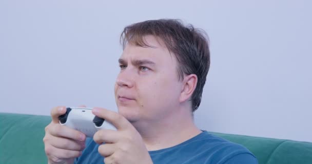 Man with console controller sta giocando intensamente al videogioco. Qualcosa lo distrae, gira la testa, solleva le sopracciglia di sorpresa, scuote la testa con scetticismo, sorride e ritorna al suo intrattenimento.. — Video Stock