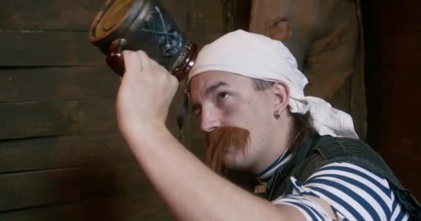 Pirate shakes empty mug in cabin and gets up walking away — Stock Video