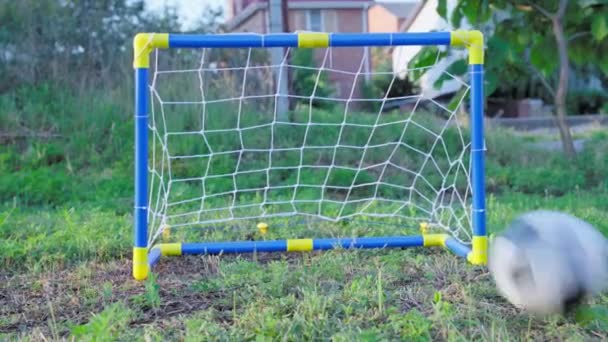 Una pelota de fútbol vuela hacia un gol de fútbol infantil. Calentamiento y entrenamiento de jugadores antes de competiciones o juegos. — Vídeo de stock