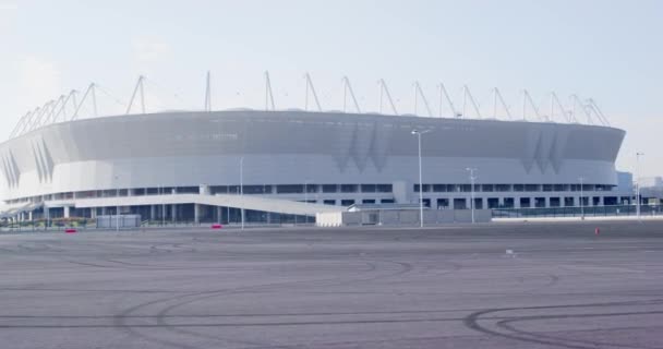 Någon kör långsamt med bil, skoter, cykel eller rullskridskor förbi en stor ny idrottsarena mot staden, en förstapersonsvy. Friluftsliv. — Stockvideo