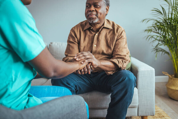 Женщина-медицинский работник, держась за руки пожилого мужчины в доме престарелых, сосредоточься на руках. Выстрел неизвестного молодого врача, держащего за руку старшего пациента в поддержку