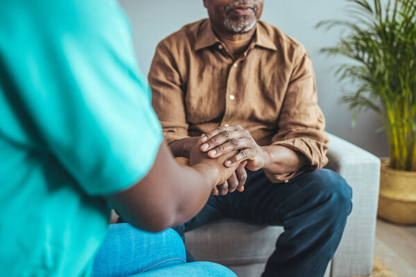 Женщина-медицинский работник, держась за руки пожилого мужчины в доме престарелых, сосредоточься на руках. Выстрел неизвестного молодого врача, держащего за руку старшего пациента в поддержку