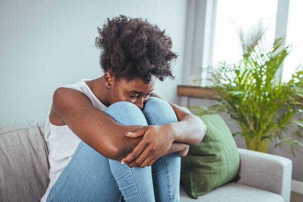 Разочарованная юная леди, сидящая на диване, обнимая подушку, смотрит в окно. Потерянная в мыслях несчастная женщина тысячелетия сожалеет о неправильном решении, проводит время в одиночестве в гостиной
.