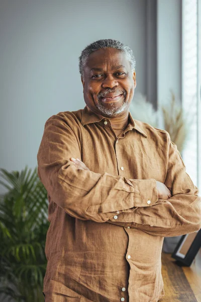 Portrait of an older man wearing a shirt on a gray background. A happy old man looks at a camera isolated over a gray wall. An older man smiles at the camera, a happy old man.