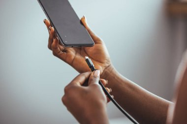 Kadın eli akıllı bir telefonun şarj aletinin fişini çekiyor. Elektrik bankası olan akıllı telefon kullanan bir kadın. Genç bir kadın akıllı telefona güç yüklüyor. Kadın cep telefonuyla şarj oluyor.