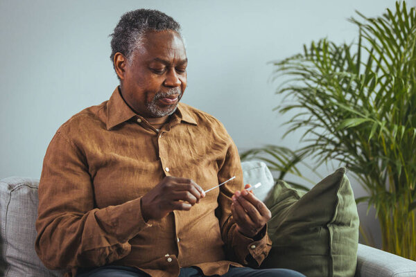 Coronavirus self test at home. senior man performs a covid-19 quick test at home. Test with cotton swab in the nose of the young man on white background, copy space space for text