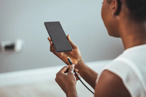Woman hands connected charger to smart phone at home. Woman hands plugging a charger on a smart phone. Woman hands charging battery in mobile smart phone