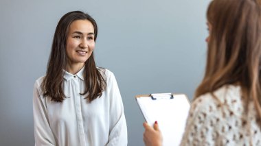 Başarılı bir psikolog hastasıyla konuşuyor. Kadın bir müşteriyle konuşurken olumlu genç kadın terapist hareketleri yapıyor. Terapist genç bayanla konuşurken sıcak bir şekilde gülümsüyor..