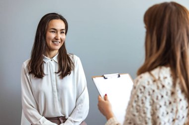 Başarılı bir terapi. Genç bayan müvekkil psikologla görüşüyor. Klinikte profesyonel yardıma minnettar. Bir psikologla terapi seansı yapan genç bir kadının fotoğrafı.
