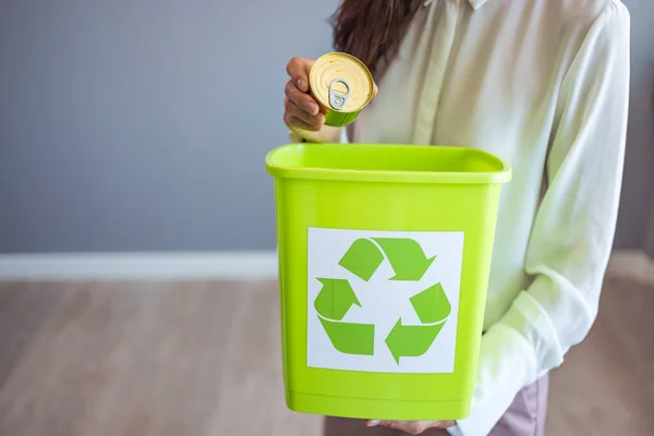 Recycling, waste sorting and sustainability concept - hand throwing tin can into rubbish bin. Woman putting a can in a garbage bin, separate waste collection and recycling concept