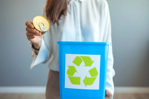 Recycling, waste sorting and sustainability concept - hand throwing tin can into rubbish bin. Woman putting a can in a garbage bin, separate waste collection and recycling concept