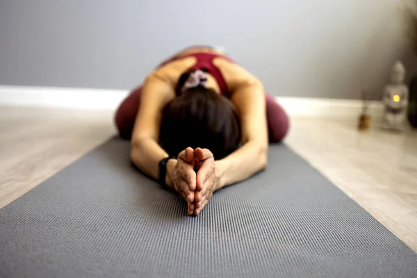 A Asian attractive woman practices yoga, stretches in an exercise, exercises, wears sportswear, an upper and trousers, in full length, studio background. The concept of yoga and training