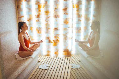 Bitiş saunasında dinlenen genç ve güzel bir kadın. Spa merkezi ve saunada sağlıklı bir hafta sonu. Sıcak bir saunada bankta oturan bikinili, mutlu ve seksi bir kadın..