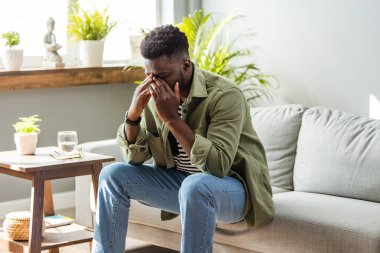 O, başını dokunmadan, kafa bükme ve ağrılar yüzünden kapalı gözlerle sırıtarak şeytanın VESVESESİNDEN gri arka plan duygu şiddetli baş ağrısı karşı yatay Afrikalı-Amerikalı adam portresi resimde