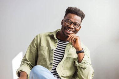 Kanepede dinlenen yakışıklı bir delikanlının fotoğrafı. Yakışıklı bir gencin portresi. Gri arka planda poz veren kendine güvenen genç bir iş adamının stüdyo fotoğrafı.