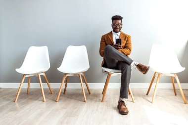Male candidate waiting for job interview. My device is a great way to keep me busy. The perfect app for a job applicant. Cropped studio shot of a businessman using a smartphone while waiting