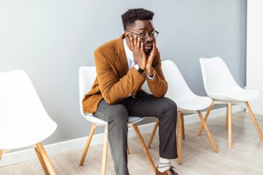 Gri arka planda bekleyen genç bir adamın stüdyo çekimi. Genç endişeli işadamı iş görüşmesini bekliyor. Sandalyede oturan bir iş adamının portresi.