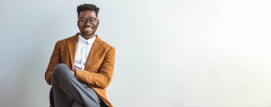 Stüdyoda sandalyede oturan Afrikalı Amerikalı adam.