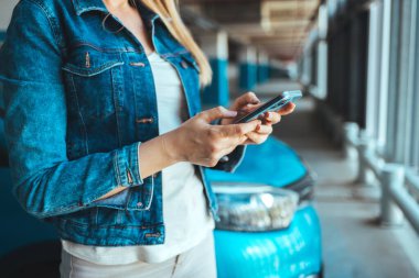 Park yerinde akıllı telefon kullanan genç bir kadının görüntüsünü kapat. 