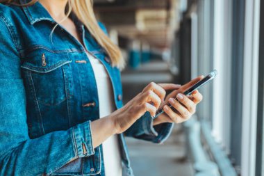 Park yerinde akıllı telefon kullanan genç bir kadının görüntüsünü kapat. 