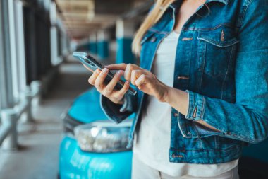 Park yerinde akıllı telefon kullanan genç bir kadının görüntüsünü kapat. 