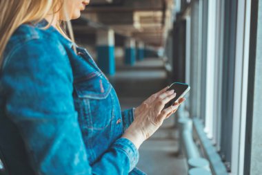 Park yerinde akıllı telefon kullanan genç bir kadının görüntüsünü kapat. 