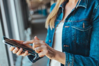 Park yerinde akıllı telefon kullanan genç bir kadının görüntüsünü kapat. 