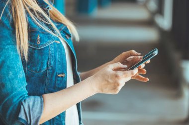 close up view of young woman using smartphone on parking lot 