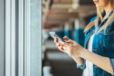 Park yerinde akıllı telefon kullanan genç bir kadının görüntüsünü kapat. 