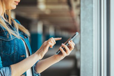 Park yerinde akıllı telefon kullanan genç bir kadının görüntüsünü kapat. 