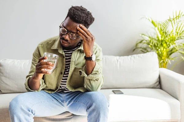 Young Man Suffering Strong Headache Migraine Sitting Glass Water Living — Zdjęcie stockowe