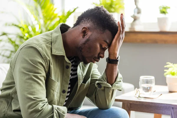 Evdeki oturma odasındaki kanepede yalnız başına oturan bir adam bunalımlı görünüyor. Evde tek başına oturan adam üzgün ve perişan görünüyor.